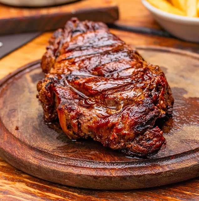 Bife jugoso a las brasas sobre tabla de madera